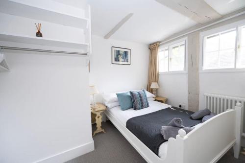 a bedroom with a white bed and two windows at Cosy cottage central Canterbury with free parking in Kent