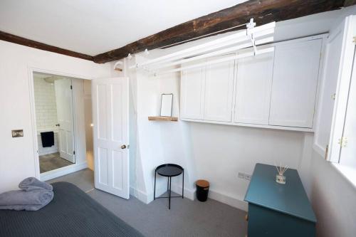 a bedroom with white cabinets and a blue desk at Cosy cottage central Canterbury with free parking in Kent
