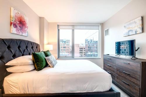 a bedroom with a bed with a dresser and a window at Luxury Apt in the Heart of Seaport in Boston