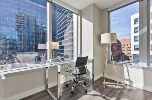 an office with a glass desk and a chair in front of a window at Modern Apt in Seaport with Gym in Boston