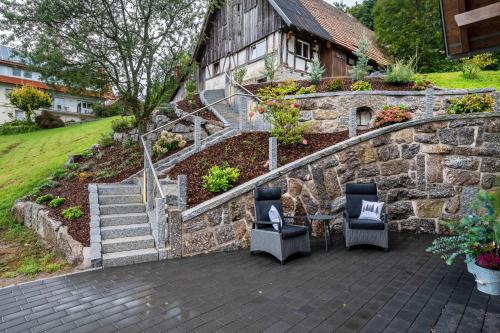 a patio with two chairs and a stone wall at Waldlux Luxus-Chalet Brennhus in Kappelrodeck