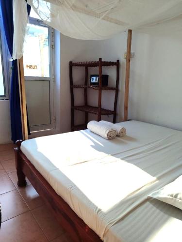 a bedroom with a bed with two towels on it at HOMELAND SWAHILI LODGE Nungwi Backpacker Apartments BUDGET in Nungwi