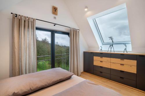 a bedroom with a large window and a dresser at Waldlux Luxus-Chalet Brennhus in Kappelrodeck