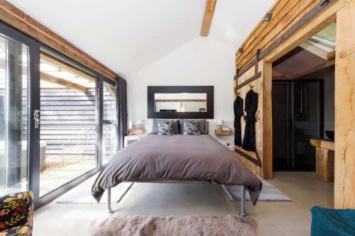 a bedroom with a bed and a large window at Romantic Countryside Lodge with Hot Tub in North Mundham