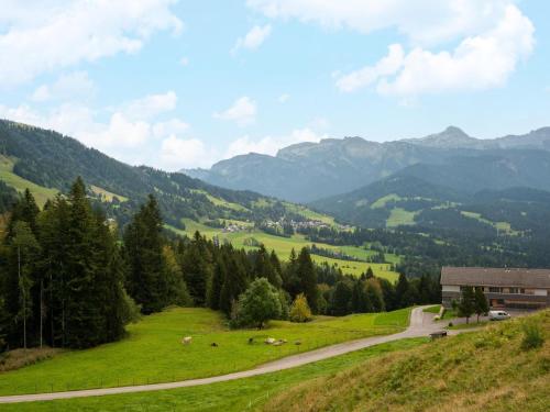 a grassy hill with a building and cows in a field at Chalet in Bregenzerwald near Ski Slopes in Sibratsgfäll