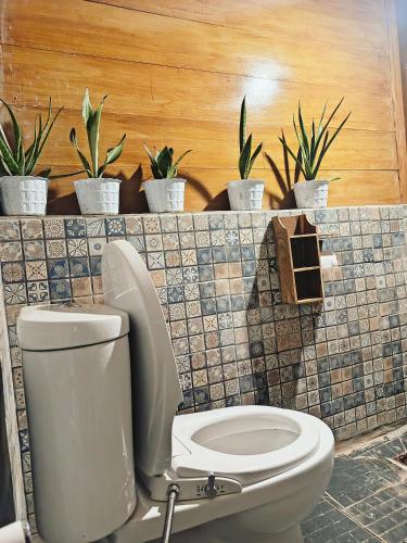 a bathroom with a toilet and a bunch of plants at Yellow Coco Gili Gede in Gili Gede