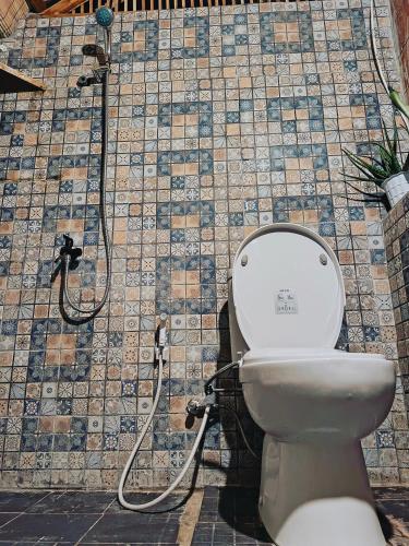 a bathroom with a toilet and a tile wall at Yellow Coco Gili Gede in Gili Gede