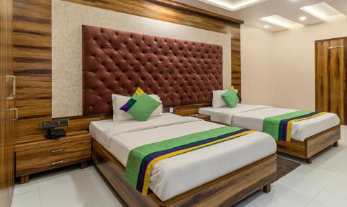 a bedroom with two beds and a large headboard at Hotel Orion Crystal in Kolkata