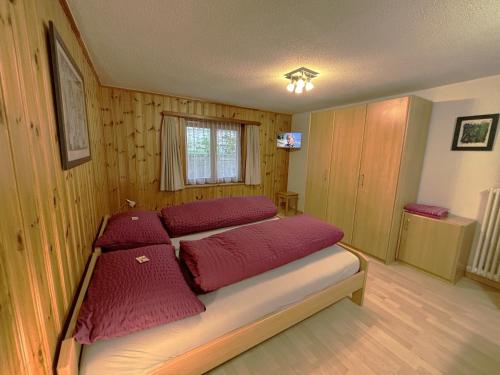 a bedroom with a bed with red pillows on it at Chalet Medi in Zermatt