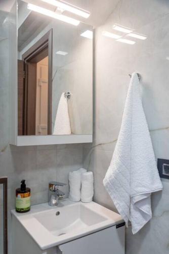a white bathroom with a sink and a mirror at Ikia Iviskos in Igoumenitsa