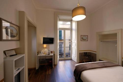 une chambre avec un lit, un bureau et une télévision dans l'établissement Napoli Class, à Naples