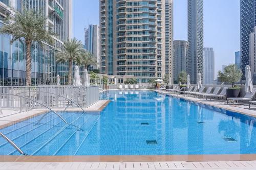 a large swimming pool in a city with tall buildings at Casa Nomad - Full Burj Khalifa & Fountain View at Luxury 4 Bed in Dubai