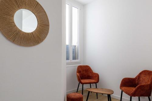 une chambre avec deux chaises et un miroir mural dans l'établissement LE LOGIS CANNOIS au calme en centre-ville, à Cannes