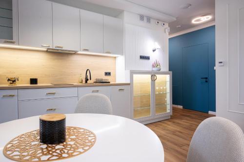 a kitchen with white cabinets and a table and chairs at Sosnowy "3" ,Baseny Tropikalne, Ładowarka do elektryków, Faktura, Parking in Kielce