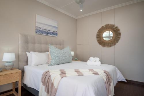 a bedroom with a white bed and a mirror at 903 Umdloti Resorts in Umdloti