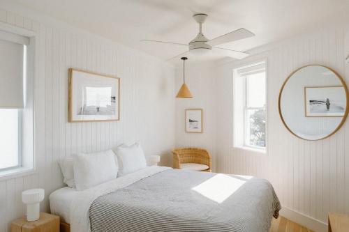 a white bedroom with a bed and a ceiling fan at The Sunsetter by WB Abodes in Wrightsville Beach