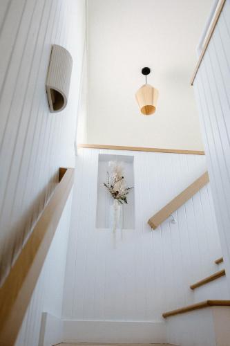 a white staircase with a vase of flowers on the wall at The Sunsetter by WB Abodes in Wrightsville Beach