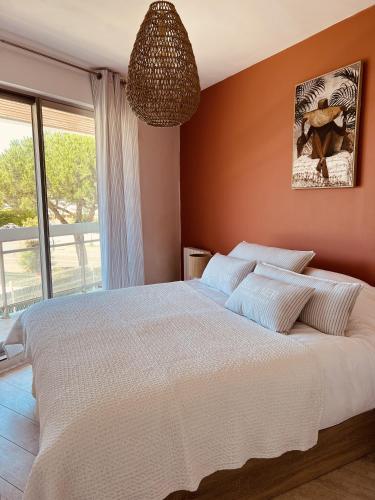 une chambre avec un grand lit et une grande fenêtre dans l'établissement Le Cocon, à Vaux-sur-Mer