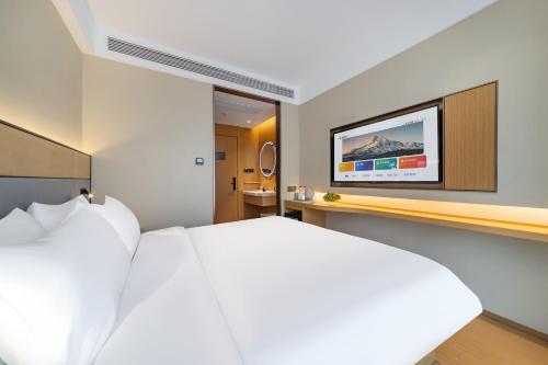 a bedroom with a bed and a tv on a wall at Yibo Hotel - Pazhou Convention and Exhibition Center - Walking distance to Canton Fair in Guangzhou