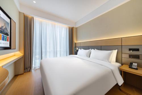 a bedroom with a large white bed and a window at Yibo Hotel - Pazhou Convention and Exhibition Center - Walking distance to Canton Fair in Guangzhou