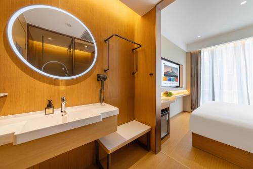 a bathroom with a bed and a sink and a mirror at Yibo Hotel - Pazhou Convention and Exhibition Center - Walking distance to Canton Fair in Guangzhou