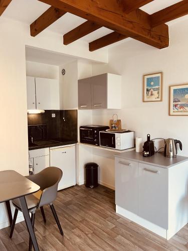 une cuisine avec des armoires blanches et une table et des chaises dans l'établissement Chaleureux Et Lumineux Duplex T2, à La Rochelle