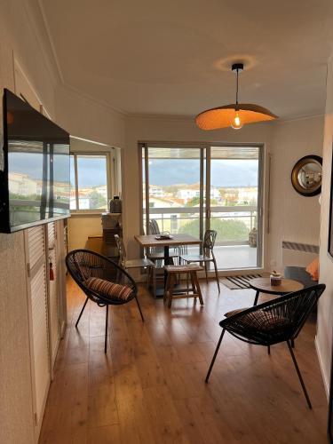 un salon avec des chaises, des tables et des fenêtres dans l'établissement Pontaillac Royan T2 Belle Terrasse, à Vaux-sur-Mer