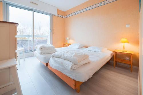 une chambre avec un lit avec des draps blancs et une fenêtre dans l'établissement Voile d'or - Appartement 3 chambres spacieux, à Le Touquet-Paris-Plage