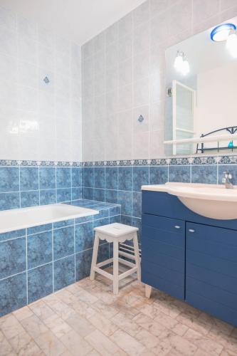 La salle de bains bleue est pourvue d'un lavabo et d'un tabouret. dans l'établissement Voile d'or - Appartement 3 chambres spacieux, à Le Touquet-Paris-Plage