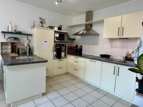 une cuisine avec des armoires blanches et des appareils électroménagers blancs dans l'établissement La Maison Oflex - à 8 min du Futuroscope, à Saint-Georges-lès-Baillargeaux