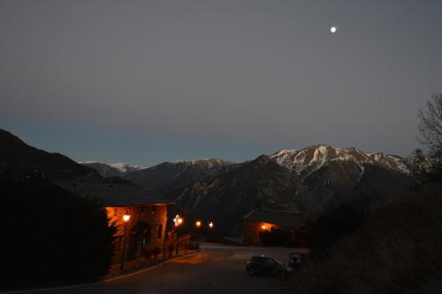 a building with lights in front of a mountain at Hotel Parador de Canolich - Only Adults in Bixessarri