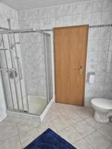 a bathroom with a shower and a toilet and a door at NEU! Ferienwohnung Doris Ostfriesland in Großefehn 
