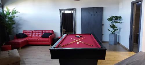 a ping pong table in a room with a red couch at Red room studio app z biljardom in Novo Mesto