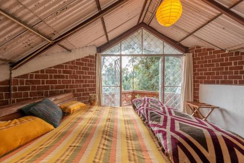 a room with a row of beds in a brick wall at Unique 2BHK in Bhowali Red Brick Quarter in Bhowāli