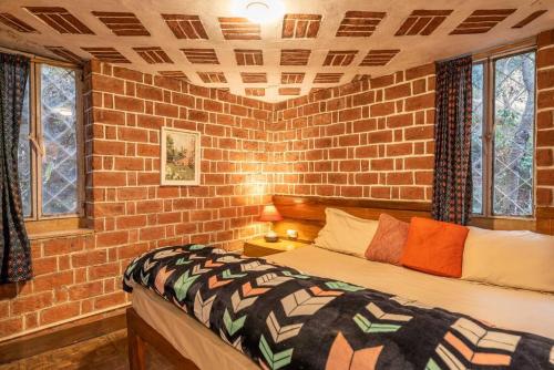 a brick walled bedroom with a bed and two windows at Unique 2BHK in Bhowali Red Brick Quarter in Bhowāli