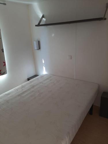 une chambre avec un lit blanc dans une pièce dans l'établissement Paisible camping les 7 fonds, à Agde