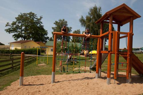 three people are sitting on a playground at Ferienanlage - Zum See & Hotel in Plau am See