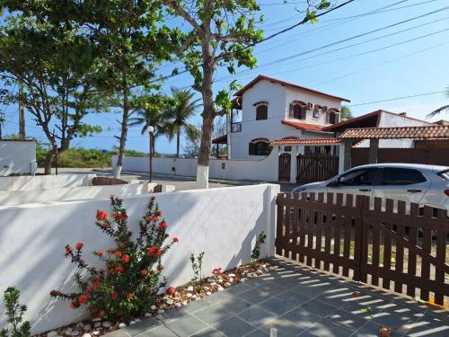 ein Haus mit einem Zaun und einem Auto in der Einfahrt in der Unterkunft Aconchegante casa à beira da praia in Maricá