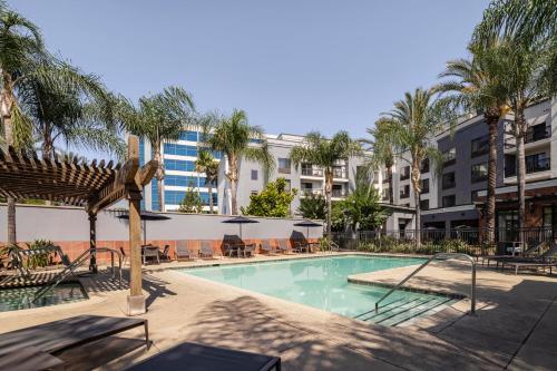 a swimming pool with palm trees and a building at Courtyard Los Angeles Burbank Airport in Burbank