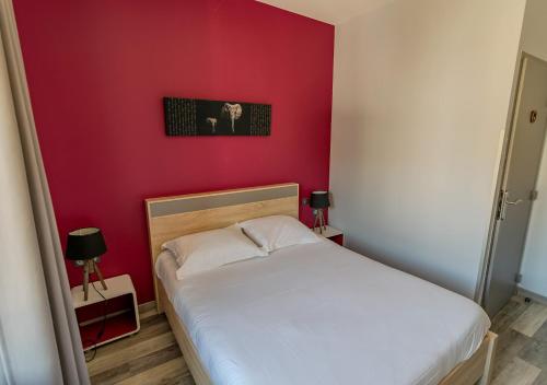 a bedroom with a white bed and a red wall at Hotel de l'Abbaye à Cluny in Cluny
