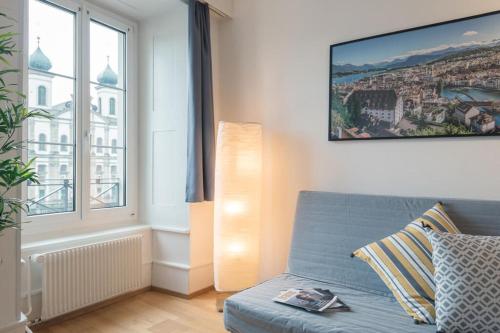 a living room with a blue couch and a window at HITrental Chapel Bridge Apartments in Luzern