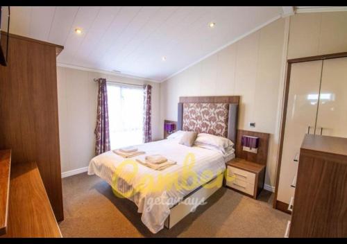 a bedroom with a bed and a dresser and a window at MP768 - Camber Sands Holiday Park - Huge Lodge - Small dog friendly - sleeps 8 in Camber