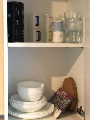 a shelf with plates and bowls and a book at Emilys 3 Room Apartment 70 qm in Hannover