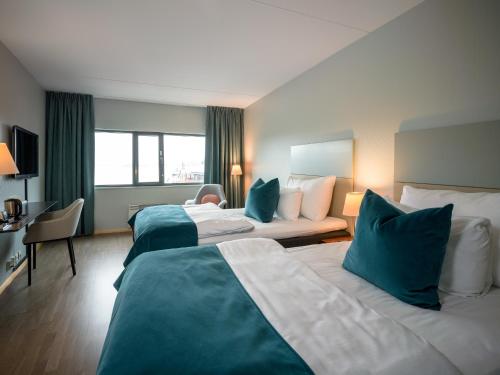 a hotel room with two beds with blue pillows at Quality Hotel Tønsberg in Tønsberg
