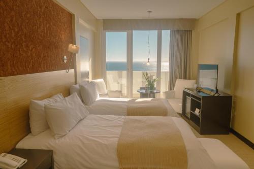a hotel room with a large bed with a view of the ocean at Rayentray Grand Hotel in Puerto Madryn