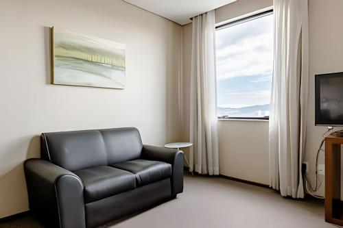 a living room with a black leather chair and a window at Flat completo, prox. a Alphaville – 1602 in Osasco