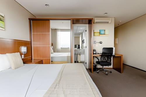 a bedroom with a bed and a desk and a chair at Flat completo, prox. a Alphaville – 1602 in Osasco