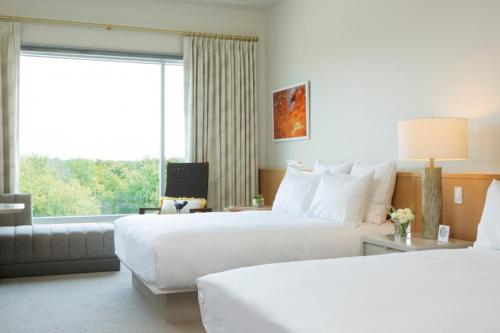 a hotel room with two beds and a large window at 21c Museum Hotel Bentonville - MGallery in Bentonville