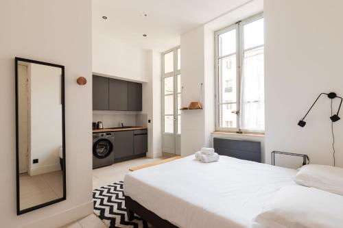 une chambre blanche avec un grand lit et un miroir dans l'établissement Dify Balcony - Quartier Ainay, à Lyon