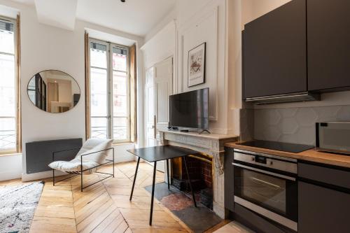 une cuisine avec une table, une télévision et un comptoir dans l'établissement Dify Balcony - Quartier Ainay, à Lyon